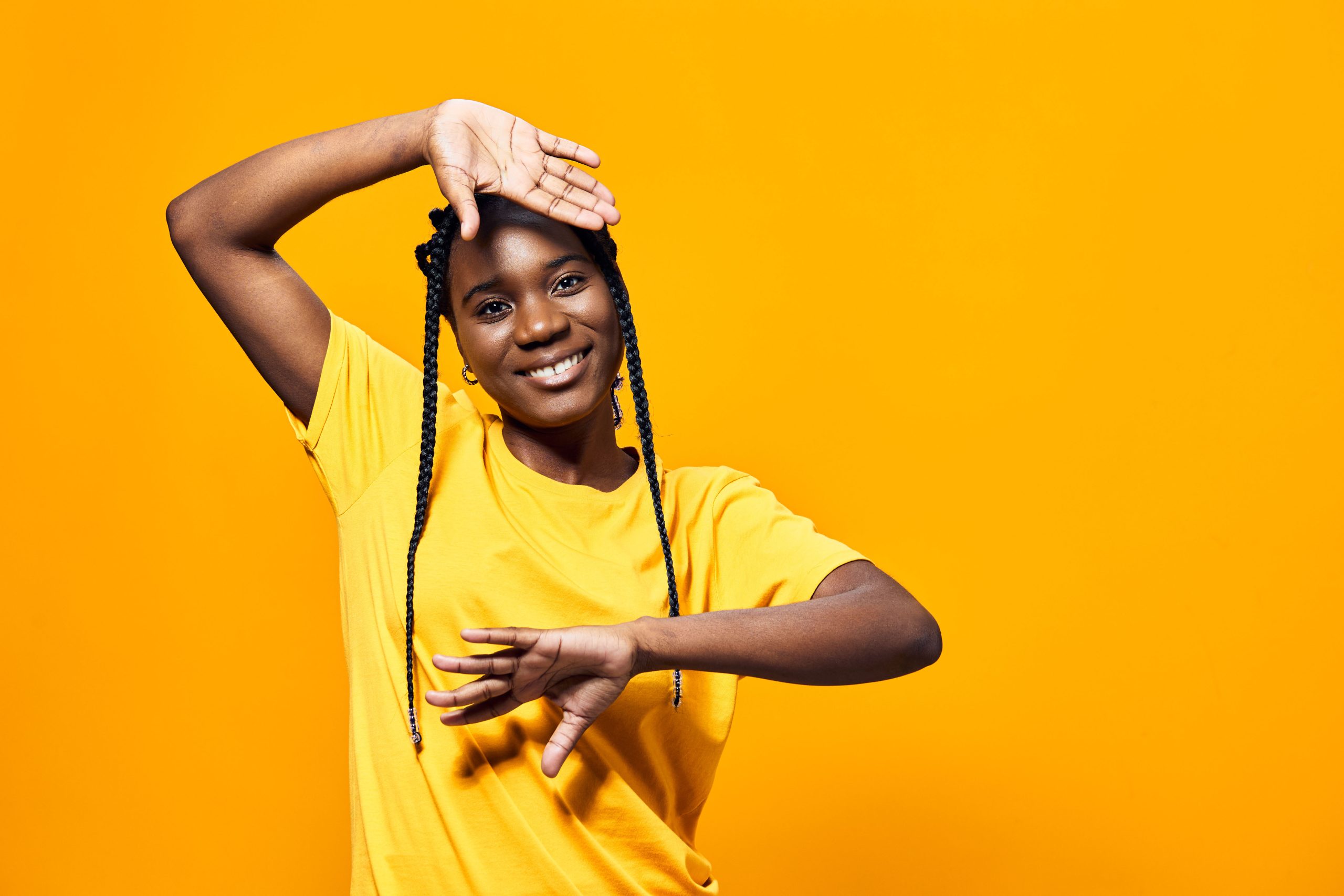 African American woman with long, neat braids smiling confidently at the camera. Hair stylist working in the background. Beauty with Braid salon website launch banner.