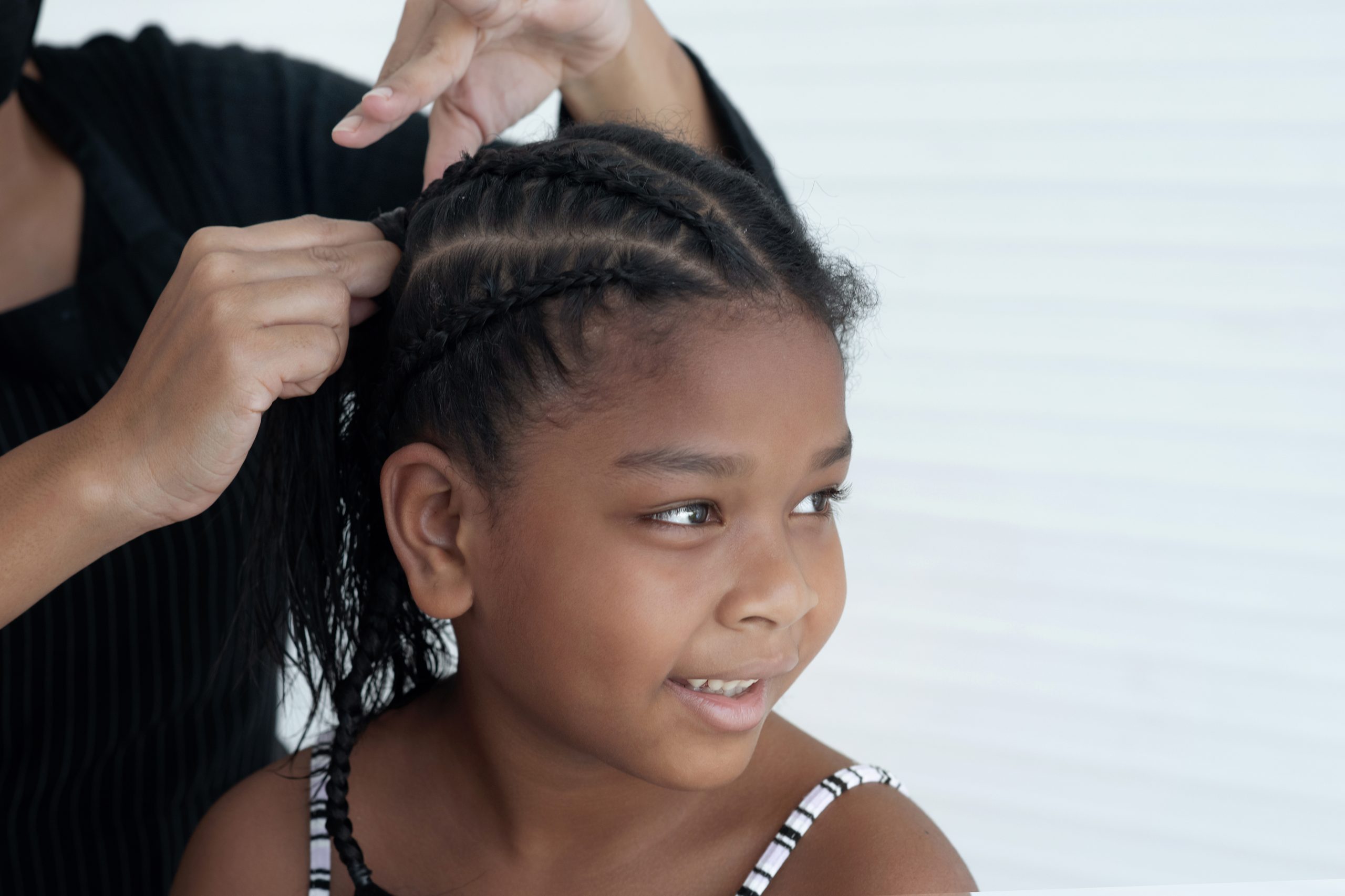 Close up of expert female hands making braids on little girl head, making Afro braids hairstyle